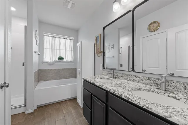 a bathroom with a granite countertop sink and mirror with bathtub