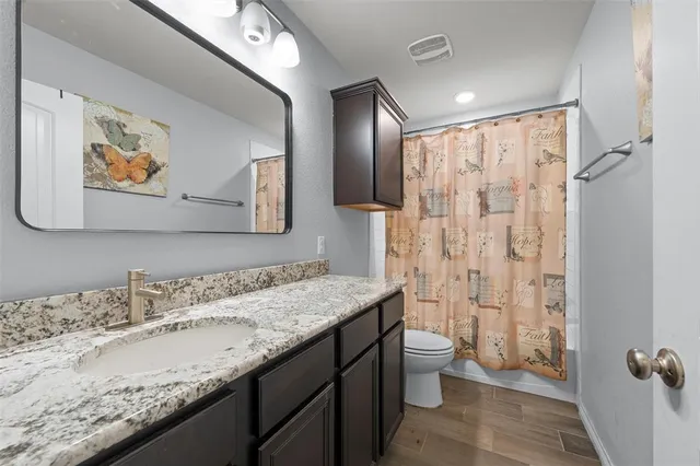 a bathroom with a granite countertop sink a toilet a shower and a mirror