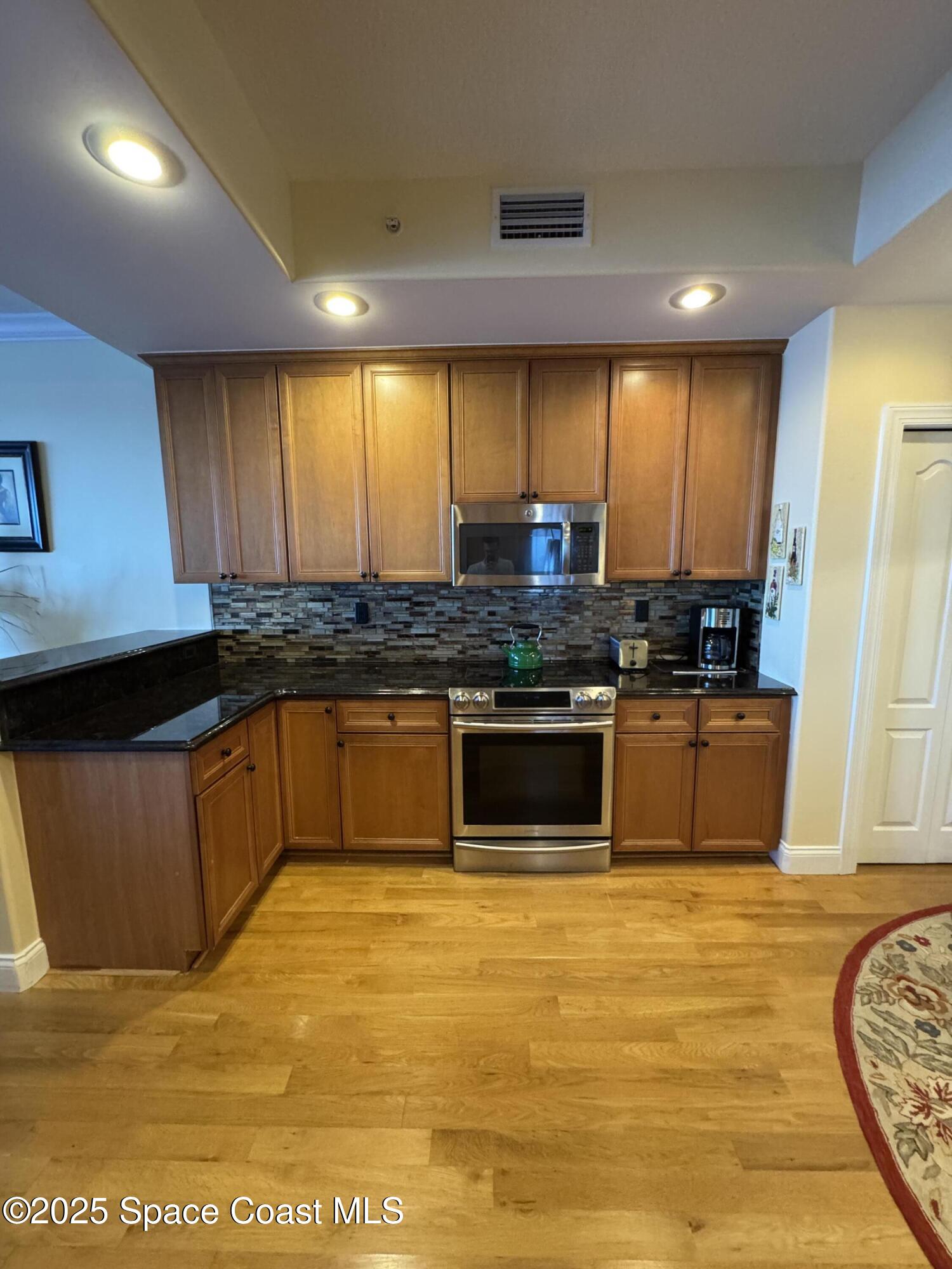 4955 Dixie Highway Northeast, Unit 502 Palm Bay, FL 32905 - Photo 9 of 51 a kitchen with stainless steel appliances wooden cabinets sink and stove