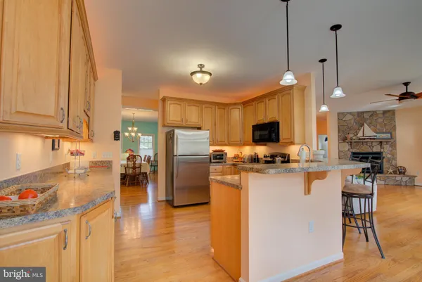 a kitchen with stainless steel appliances granite countertop wooden cabinets a sink dishwasher a stove and a wooden floors