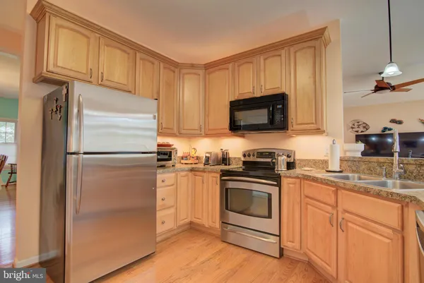 a kitchen with stainless steel appliances granite countertop hardwood floor sink stove dining table and chairs