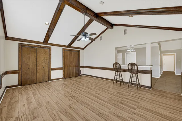a view of an empty room with a window and wooden floor