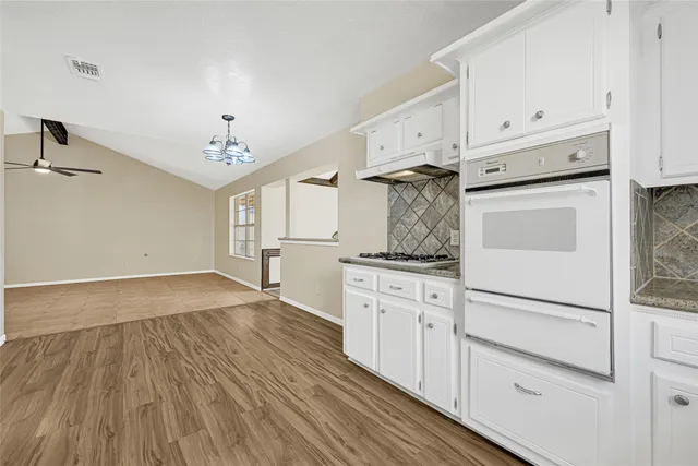 a view of an empty room with wooden floor and furniture