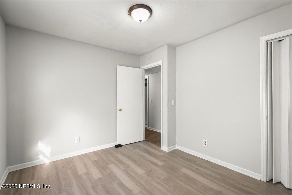 7567 Strato Road Jacksonville, FL 32210 - Photo 13 of 26 an empty room with wooden floor and windows
