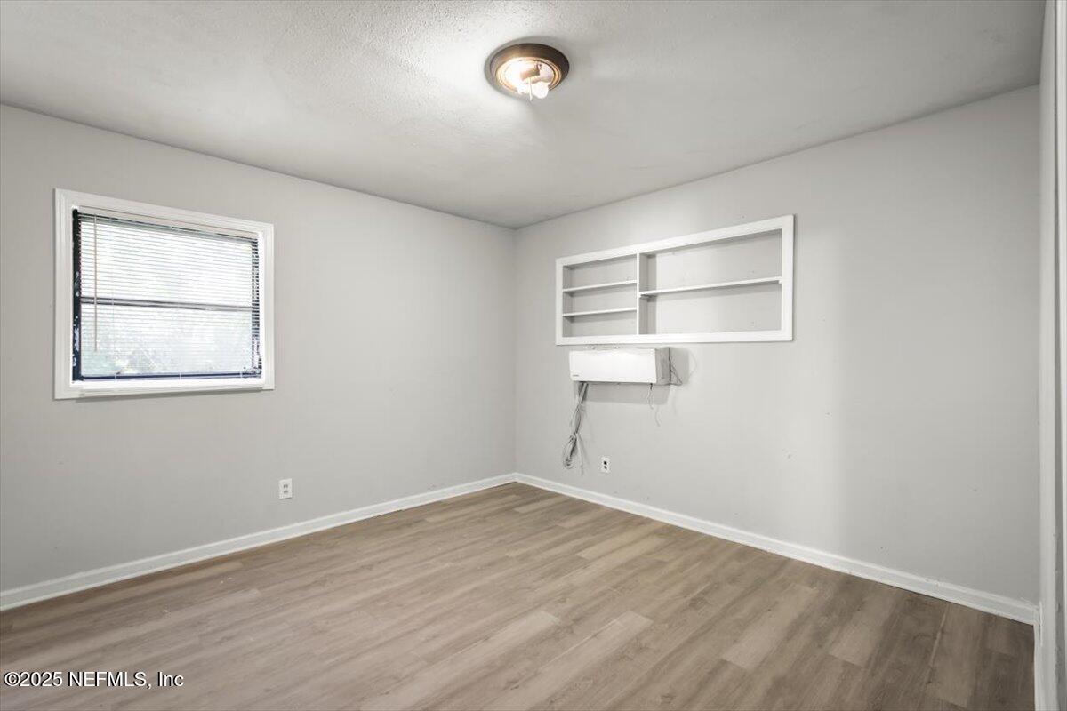 7567 Strato Road Jacksonville, FL 32210 - Photo 18 of 26 an empty room with wooden floor and windows