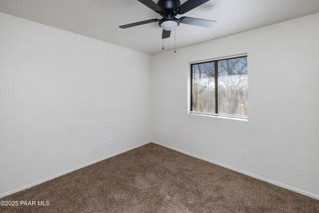a view of empty room with window and ceiling fan