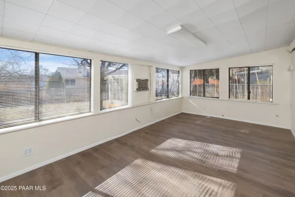 a view of an empty room with a window and wooden floor