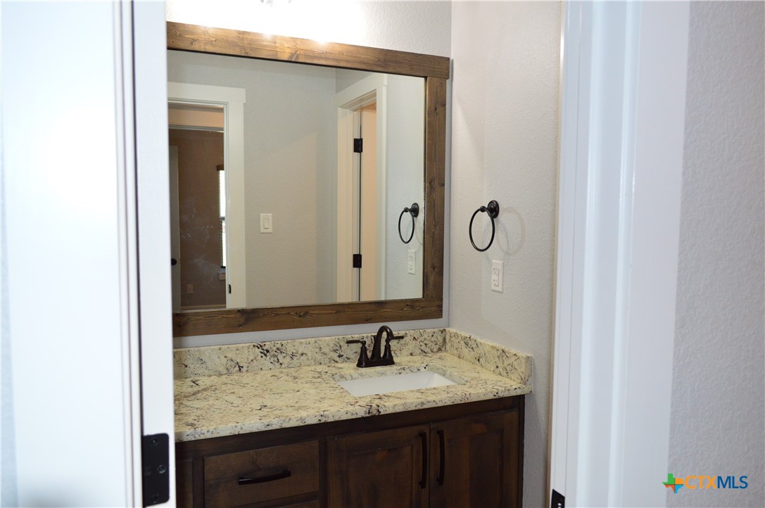 1026 County Road 3152 Kempner, TX 76539 - Photo 29 of 48 Hall Full Bath with Granite Countertop, Framed Mirror, and Door Between the Sink Area and the Tub/Shower