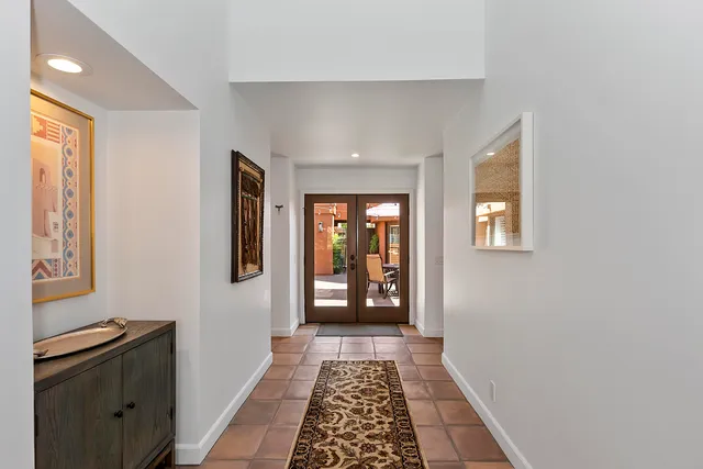 a view of a hallway to a livingroom with wooden floor and windows