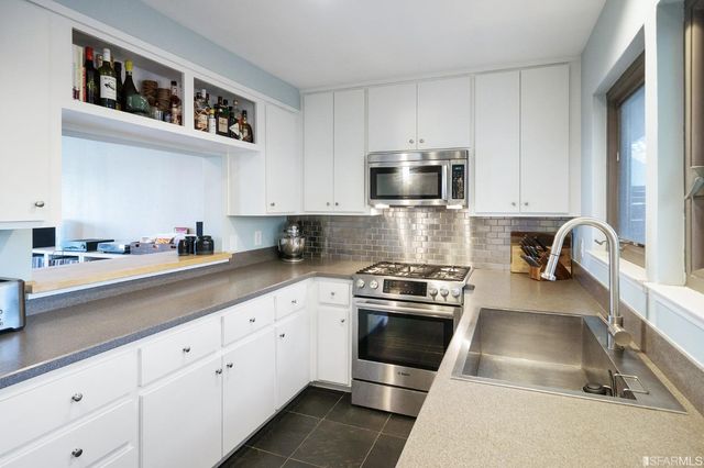 a kitchen with stainless steel appliances granite countertop a stove a sink and a microwave