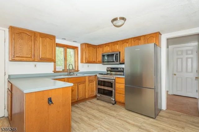 a kitchen with stainless steel appliances granite countertop a refrigerator a sink dishwasher a stove with wooden cabinets and floors