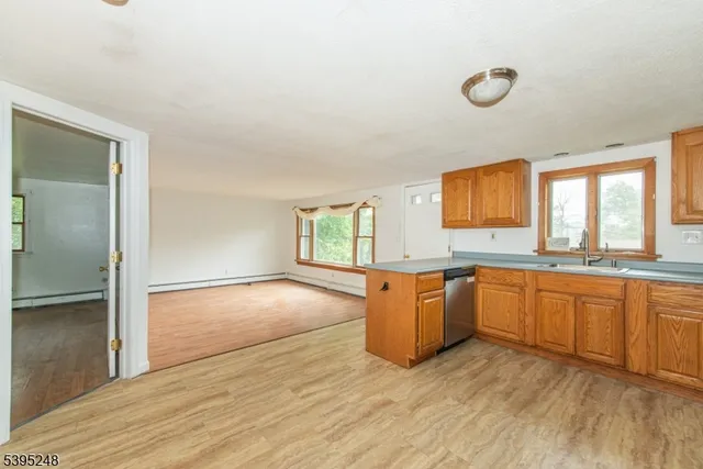 a large kitchen with granite countertop a stove a sink dishwasher and a refrigerator with wooden floor