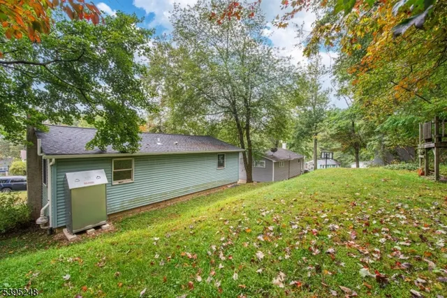 a backyard of a house with plants and large tree