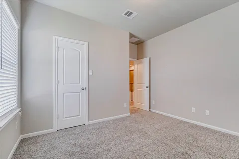 an empty room with ceiling fan and windows