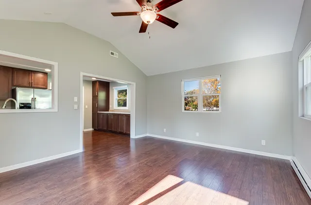 a view of an empty room with window and wooden floor