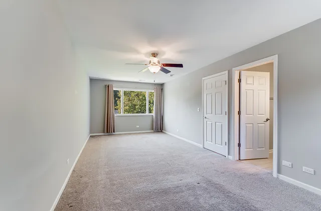an empty room with a ceiling fan and a window