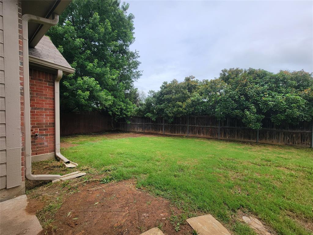 1604 Knoll Ridge Circle Corinth, TX 76210 - Photo 34 of 37 Expansive grassy backyard featuring a full privacy fence, mature trees along the perimeter, and a brick exterior wall with siding accents