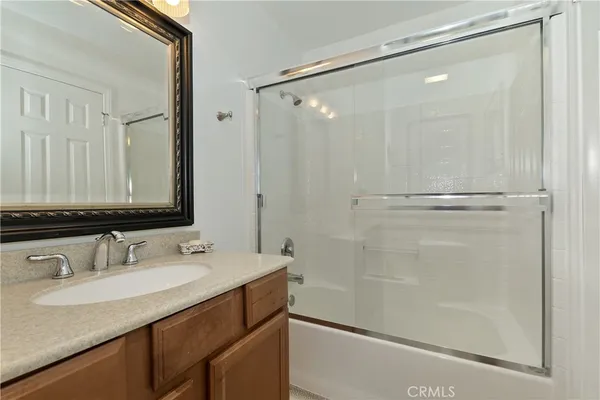 a bathroom with a granite countertop sink mirror and a shower