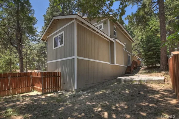 a view of backyard with wooden fence and trees