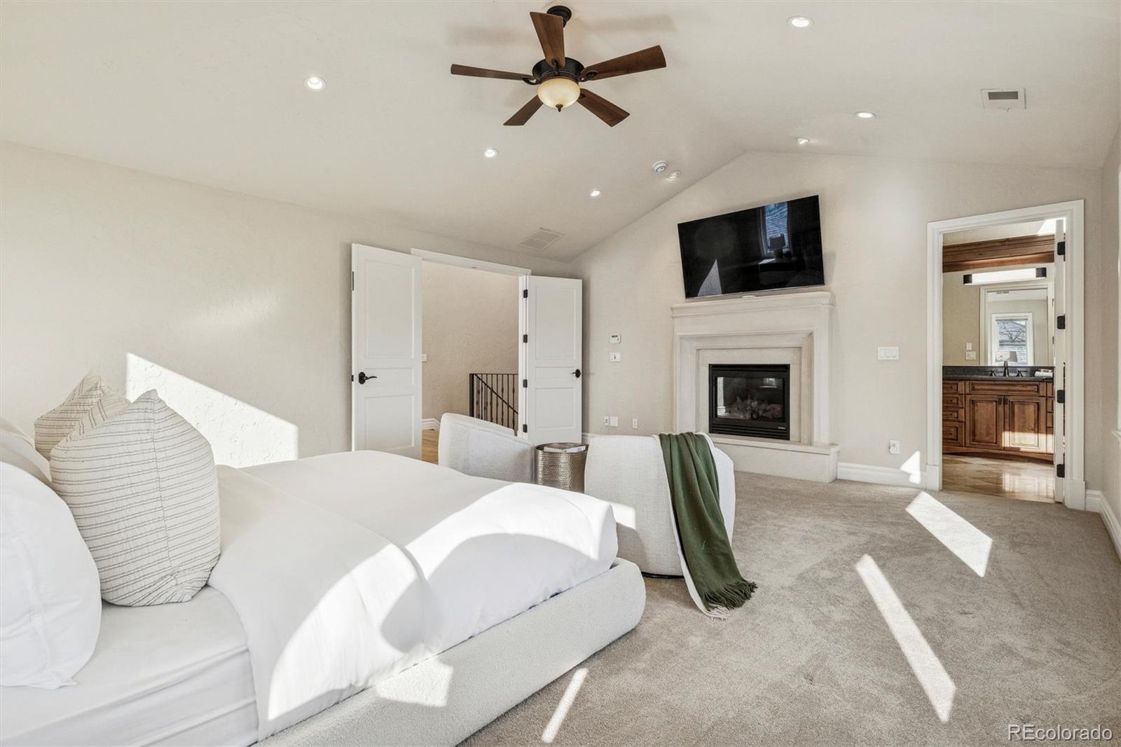 542 Adams Street Denver, CO 80206 - Photo 15 of 31 a spacious bedroom with a large bed a flat tv screen and a fireplace