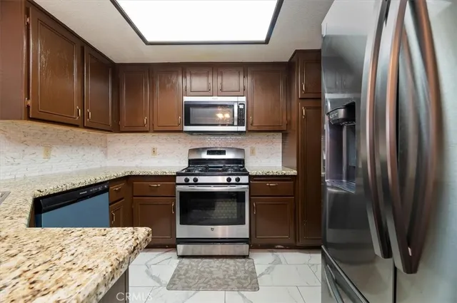 a kitchen with granite countertop a refrigerator and a stove top oven