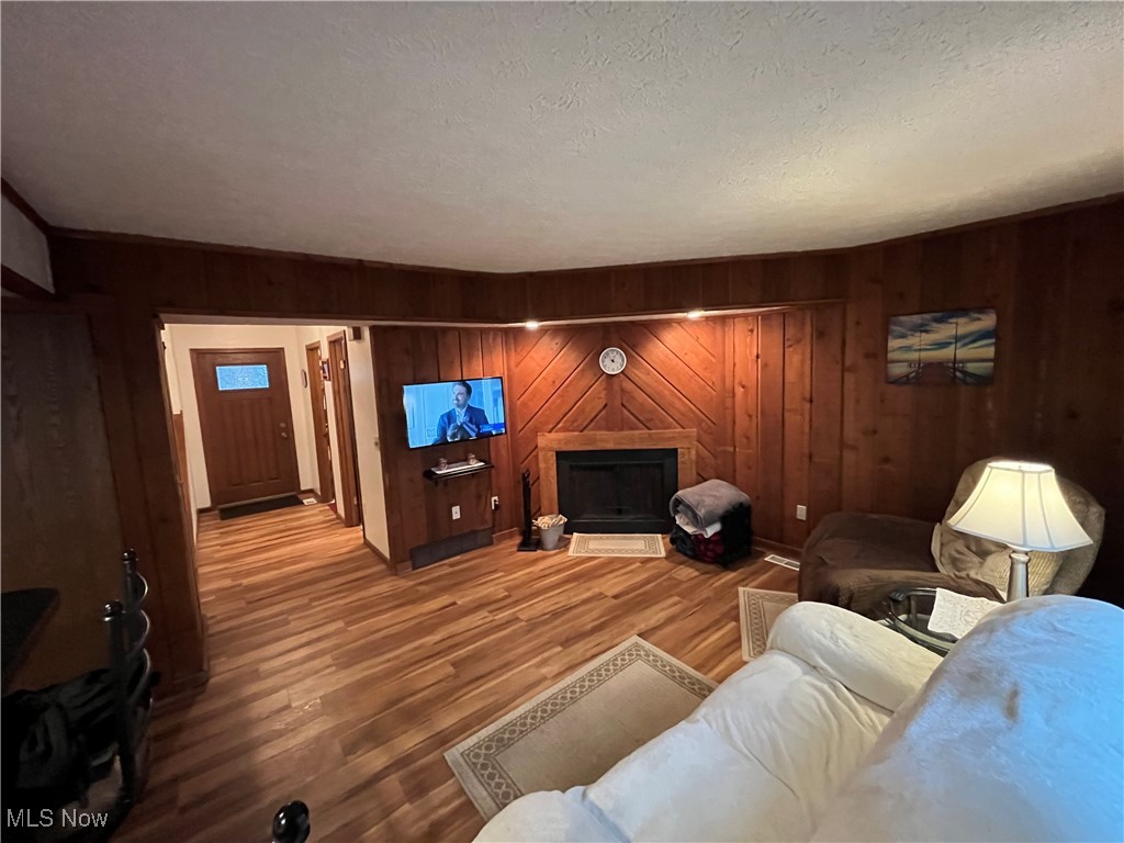 1455 Welch Road Painesville, OH 44077 - Photo 7 of 42 Living area with a fireplace, wooden walls, wood finished floors, and a textured ceiling