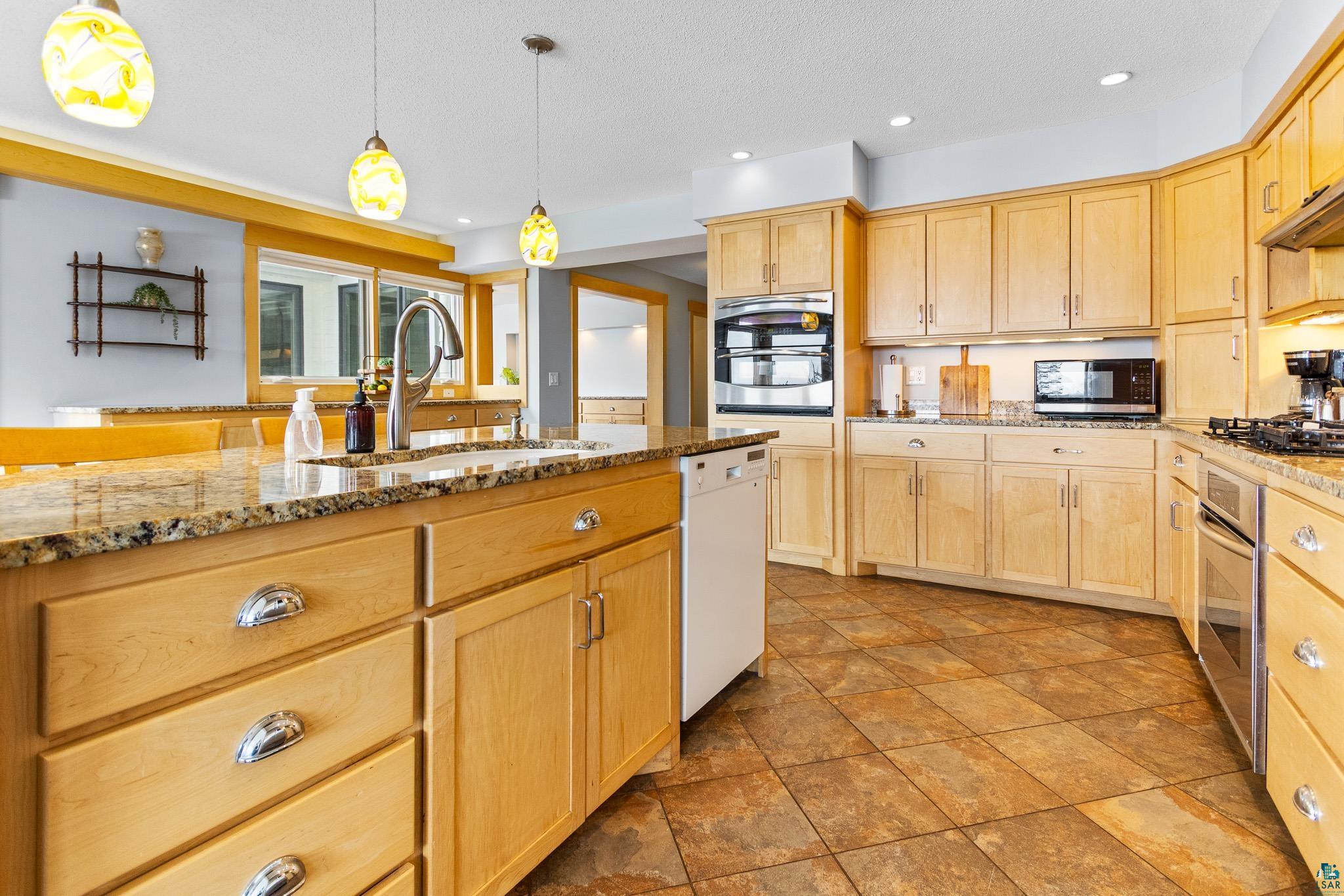 5163 Greenwood Road Duluth, MN 55804 - Photo 13 of 47 Kitchen featuring extensive wood cabinetry, stone countertops, stainless steel appliances, and tiled flooring