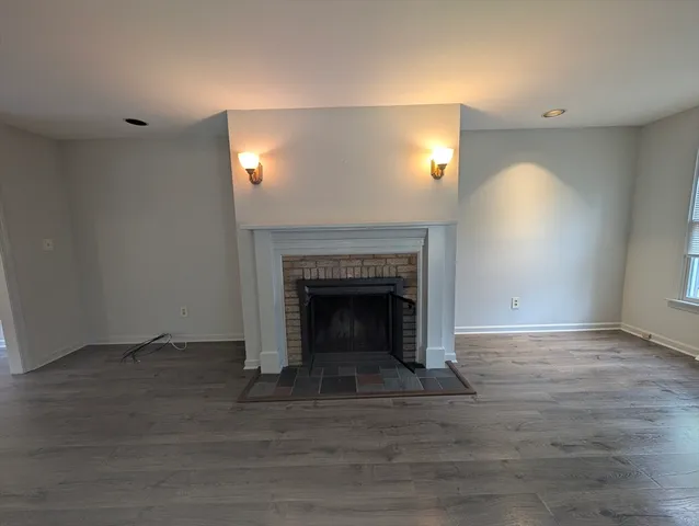 a view of an empty room with wooden floor and a fireplace
