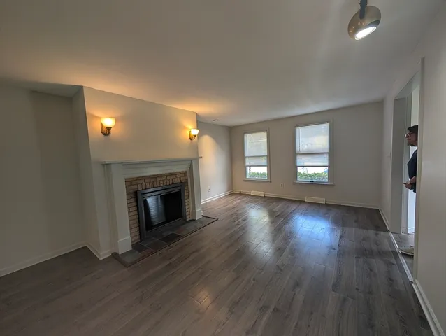 an empty room with wooden floor fireplace and windows