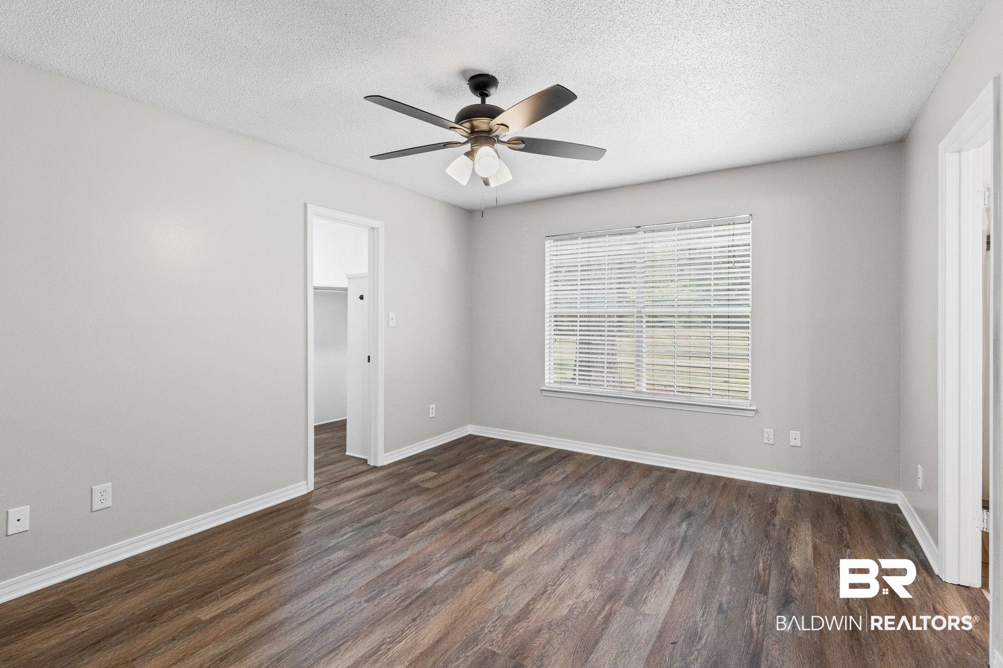 1301 Repoll Road Mobile, AL 36695 - Photo 16 of 21 Spacious room featuring wood-finish flooring, light grey walls, a ceiling fan with integrated lighting, and a large window with blinds