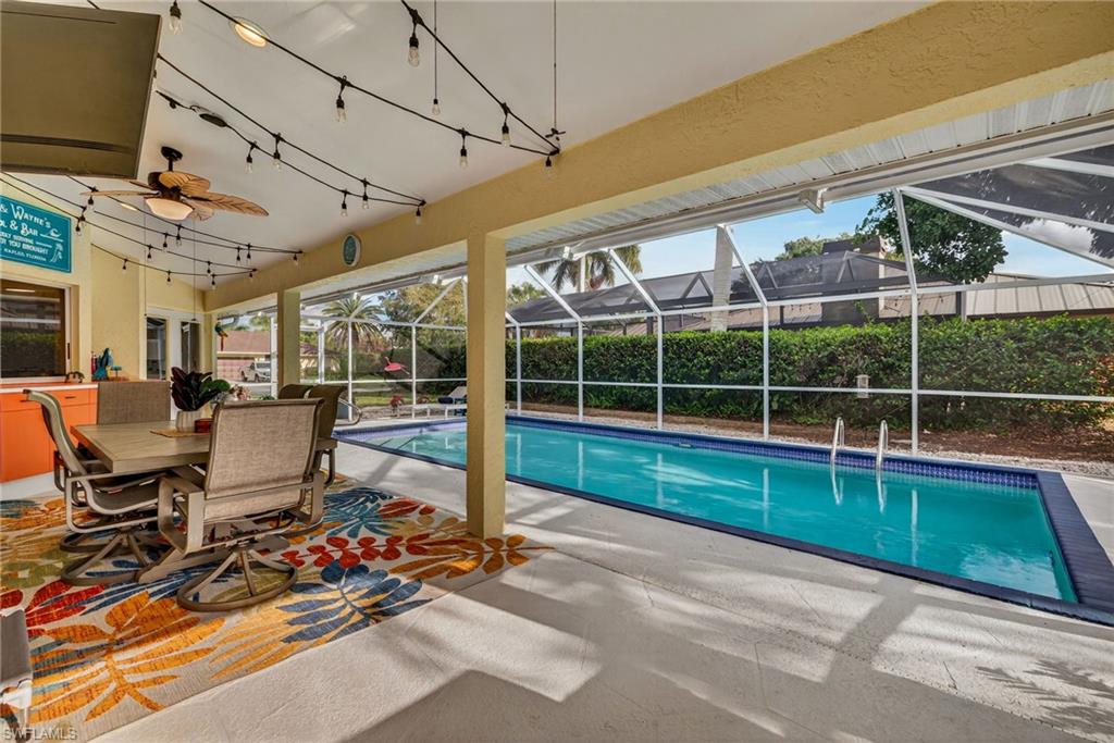 390 St Andrews Boulevard Naples, FL 34113 - Photo 1 of 42 View of swimming pool with patio surround, outdoor dining space, a sunroom, and a lanai