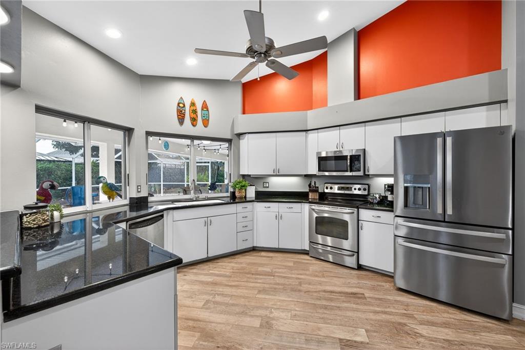 390 St Andrews Boulevard Naples, FL 34113 - Photo 10 of 42 Kitchen with stainless steel appliances, a high ceiling, light wood-style flooring, white cabinets, and a ceiling fan