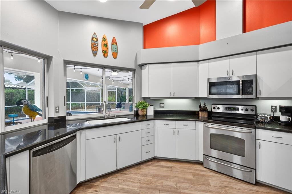 390 St Andrews Boulevard Naples, FL 34113 - Photo 11 of 42 Kitchen with white cabinets, stainless steel appliances, light wood-style floors, a ceiling fan, and a high ceiling