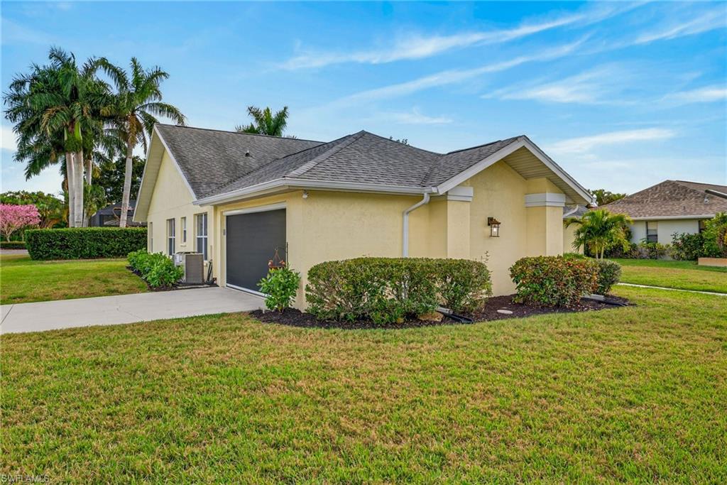 390 St Andrews Boulevard Naples, FL 34113 - Photo 4 of 42 View of front of home featuring a front lawn, stucco siding, driveway, a garage, and a shingled roof