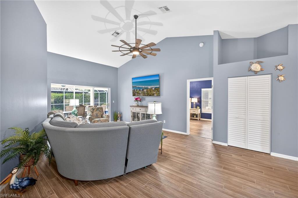 390 St Andrews Boulevard Naples, FL 34113 - Photo 6 of 42 Living room featuring ceiling fan, wood tiled floors, and vaulted ceiling