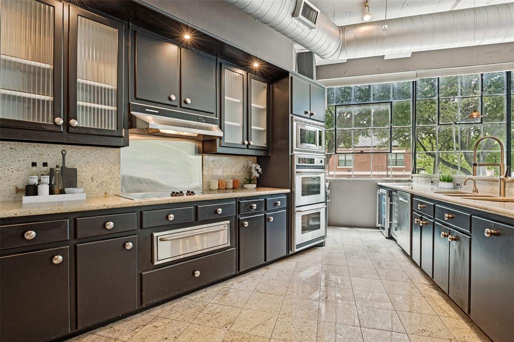 2220 Canton Street, Unit 101 Dallas, TX 75201 - Photo 2 of 20 Modern kitchen featuring a wall of window panes, dark cabinetry, light countertops, and light tile flooring