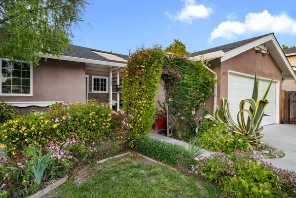 a view of a house with potted plants and a bench