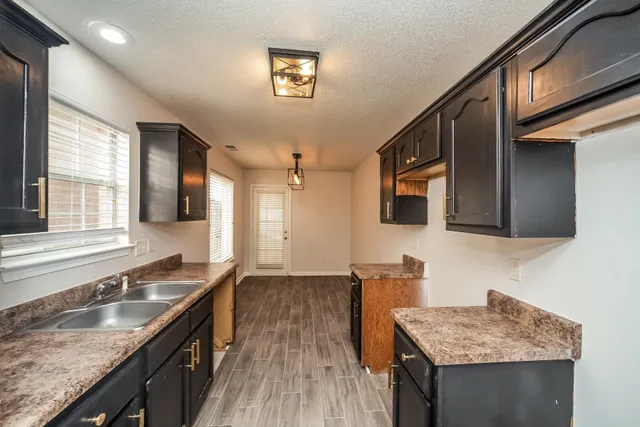 a kitchen with granite countertop a sink a counter space and cabinets