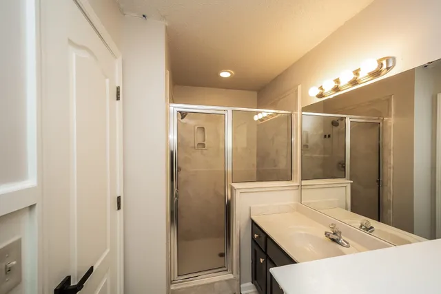 a bathroom with a sink shower and a mirror