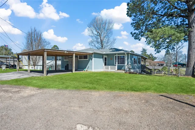 a view of a house next to a big yard and large trees