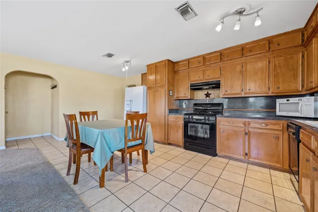 a kitchen with stainless steel appliances granite countertop a stove top oven a sink dishwasher and a refrigerator