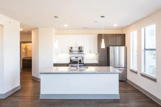 a large kitchen with stainless steel appliances granite countertop a large counter top a refrigerator and cabinets