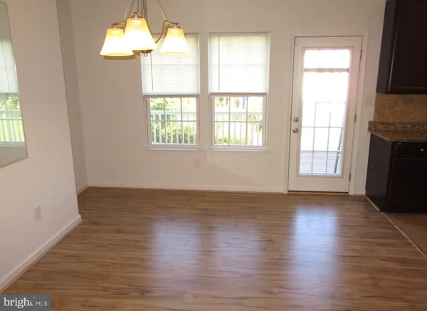 an empty room with wooden floor chandelier and windows