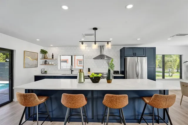a kitchen with stainless steel appliances granite countertop a table and chairs in it