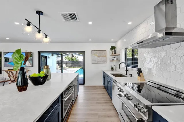 a kitchen with stainless steel appliances granite countertop a refrigerator a sink a stove a dining table and chairs