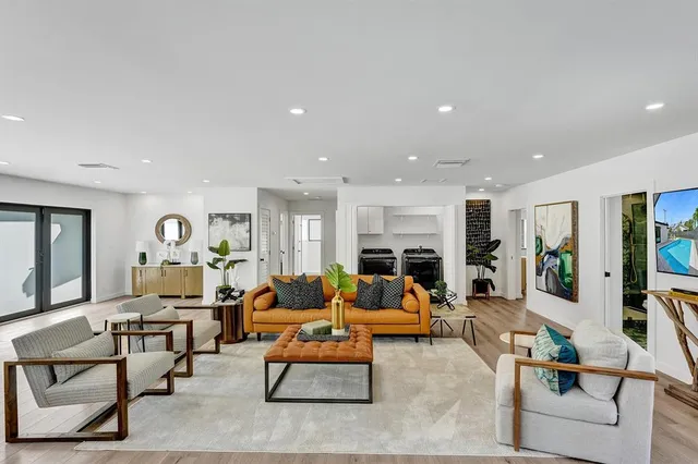 a living room with furniture kitchen view and a large window