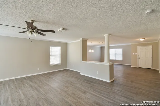 a view of empty room with wooden floor and fan