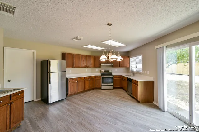 a large kitchen with a center island wooden floor stainless steel appliances and windows