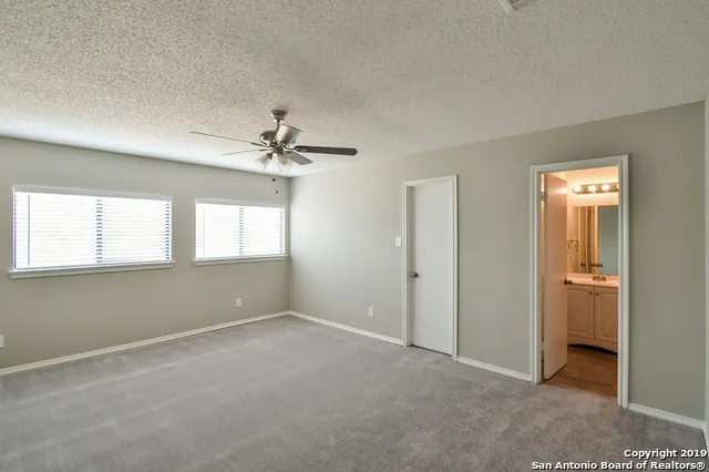 an empty room that has a window and a ceiling fan