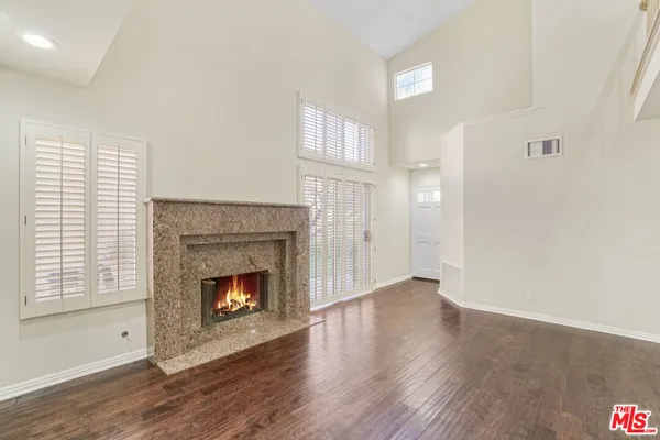 a view of an empty room with wooden floor fireplace and a window